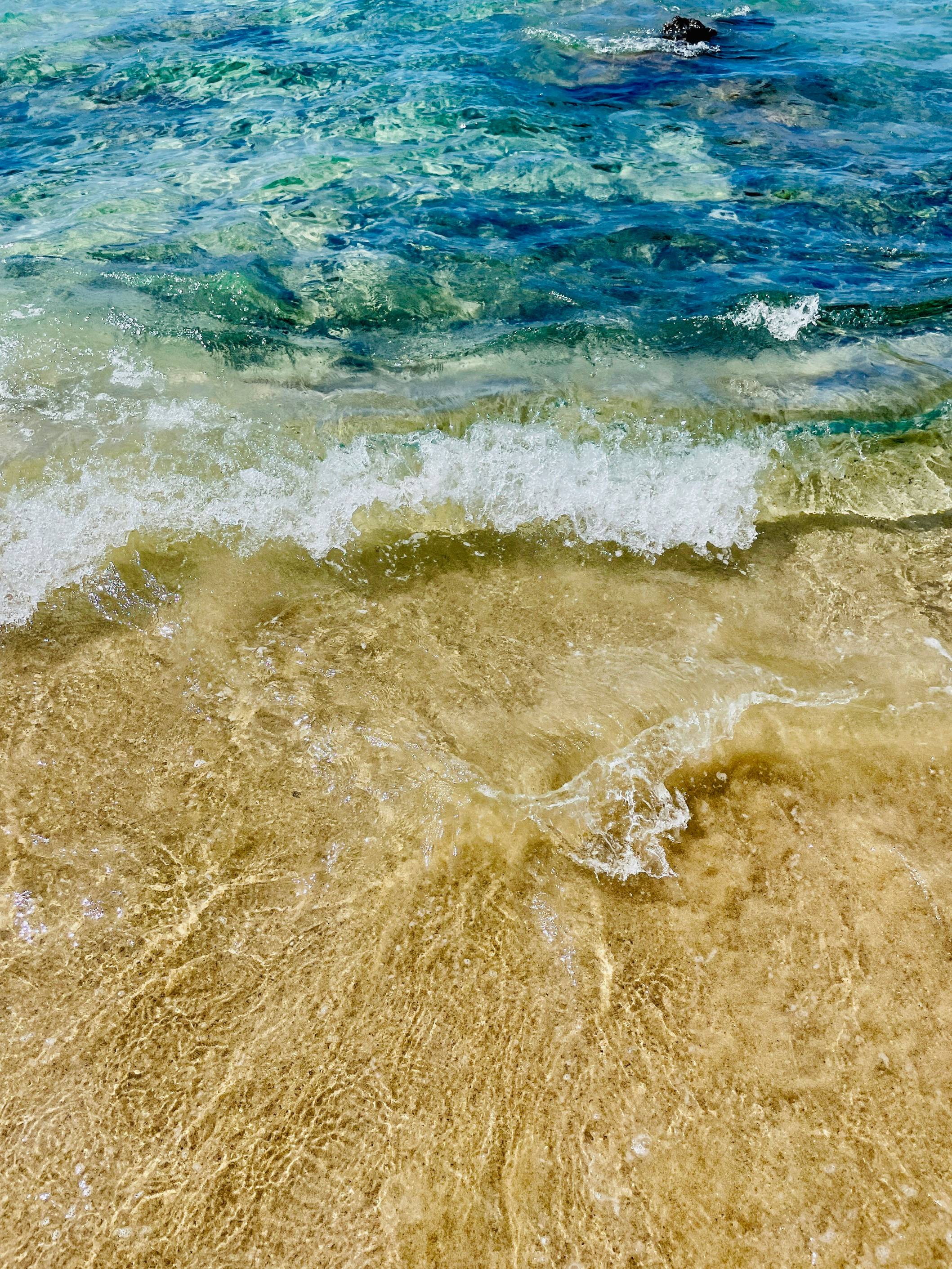 A sandy beach with waves coming in and out of the water